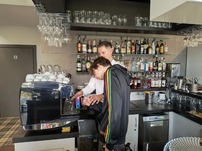 Jeden z praktykantów robi kawę według wskazówek barysty