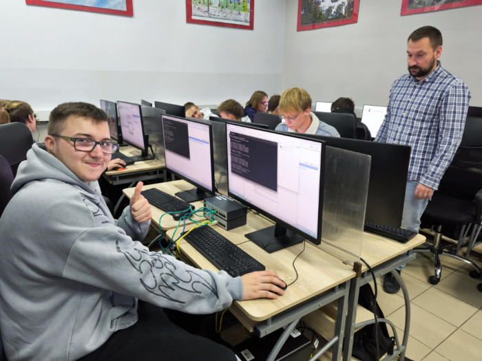 Uczniowie siedzą przy biurkach i pracują na komputerach