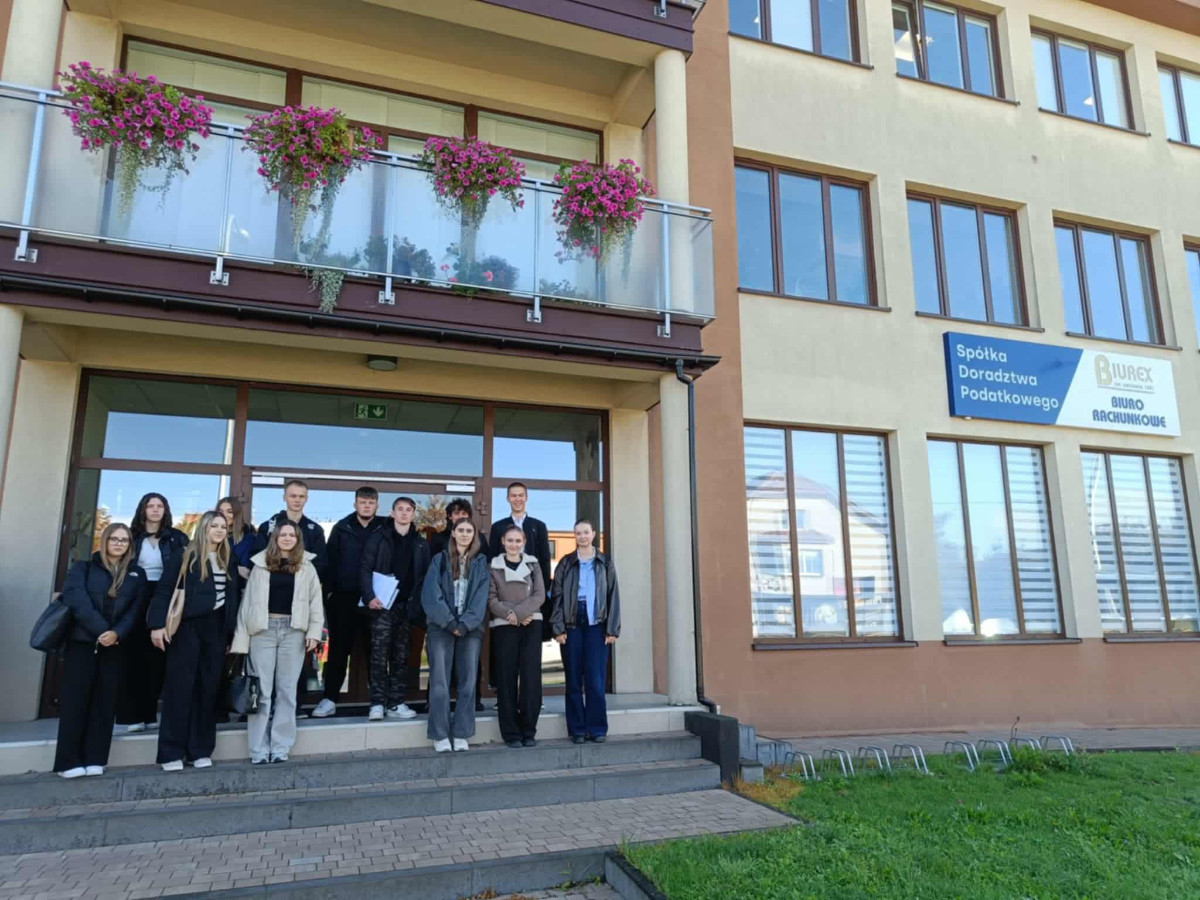 Uczniowie stoją przez budynkiem firmy Biurex