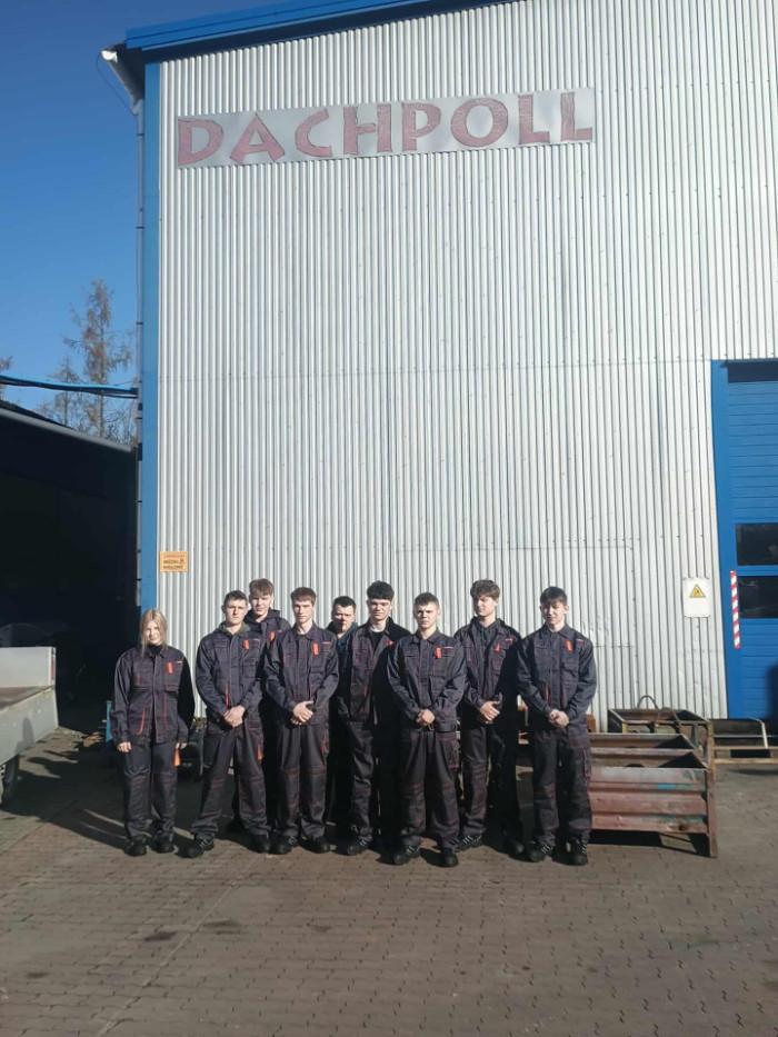 Uczniowie stoją przed bugynkiem firmy DachPoll