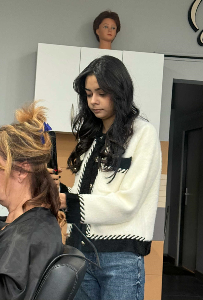 Uczennica układa włosy klientce salonu fryzjerskiego