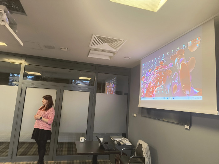 Prowadząca spotkanie i tablica na której widać prezentację