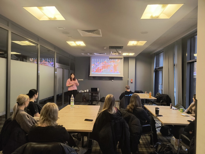 Uczniowie i prowadząca spotkanie. Widok z tyłu sali