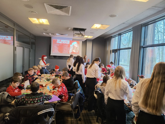 Dzieci i opiekunowie uczestniczący w warsztatach przy stolikach