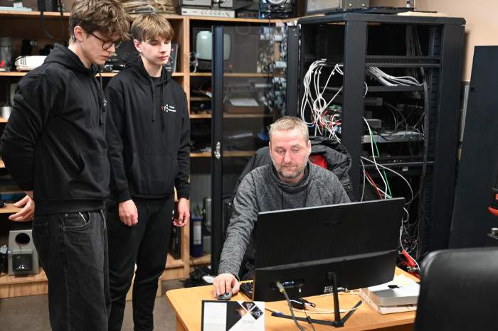 Uczniowie obserwują pracę technika przy komputerze